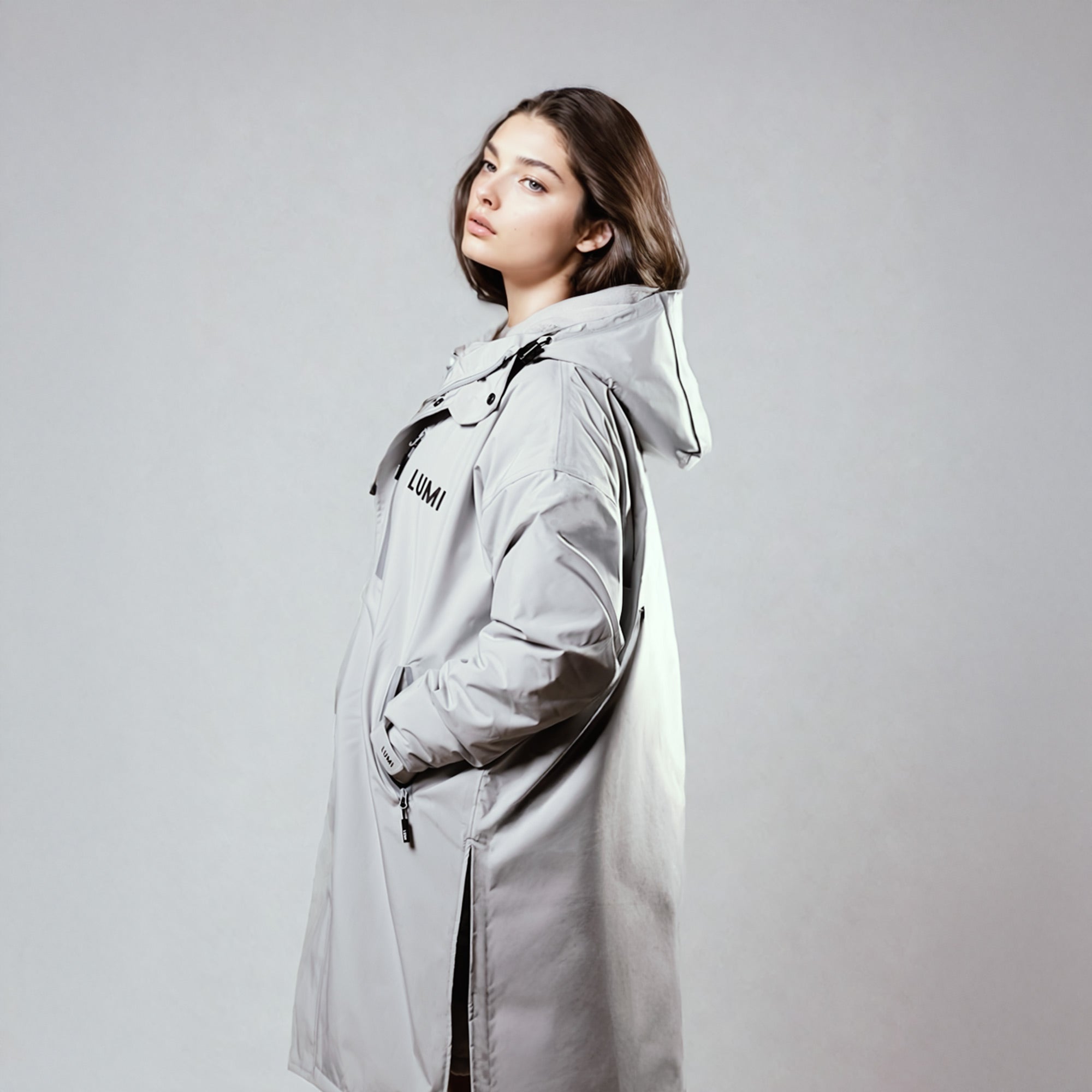 PRO DUO Changing Robe in grey shown as a stylish Nordic-inspired jacket with hood, featuring waterproof exterior and side zipper details against a neutral studio background. Demonstrates sleek silhouette and practical design elements of the changing robe.