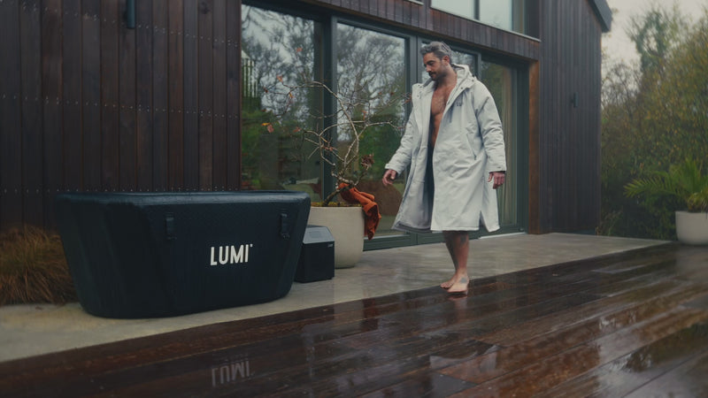 Video of a man wearing the LUMI RobePRO and swimshorts, getting in the LUMI Pro Duo ice bath, focused on cold water recovery.